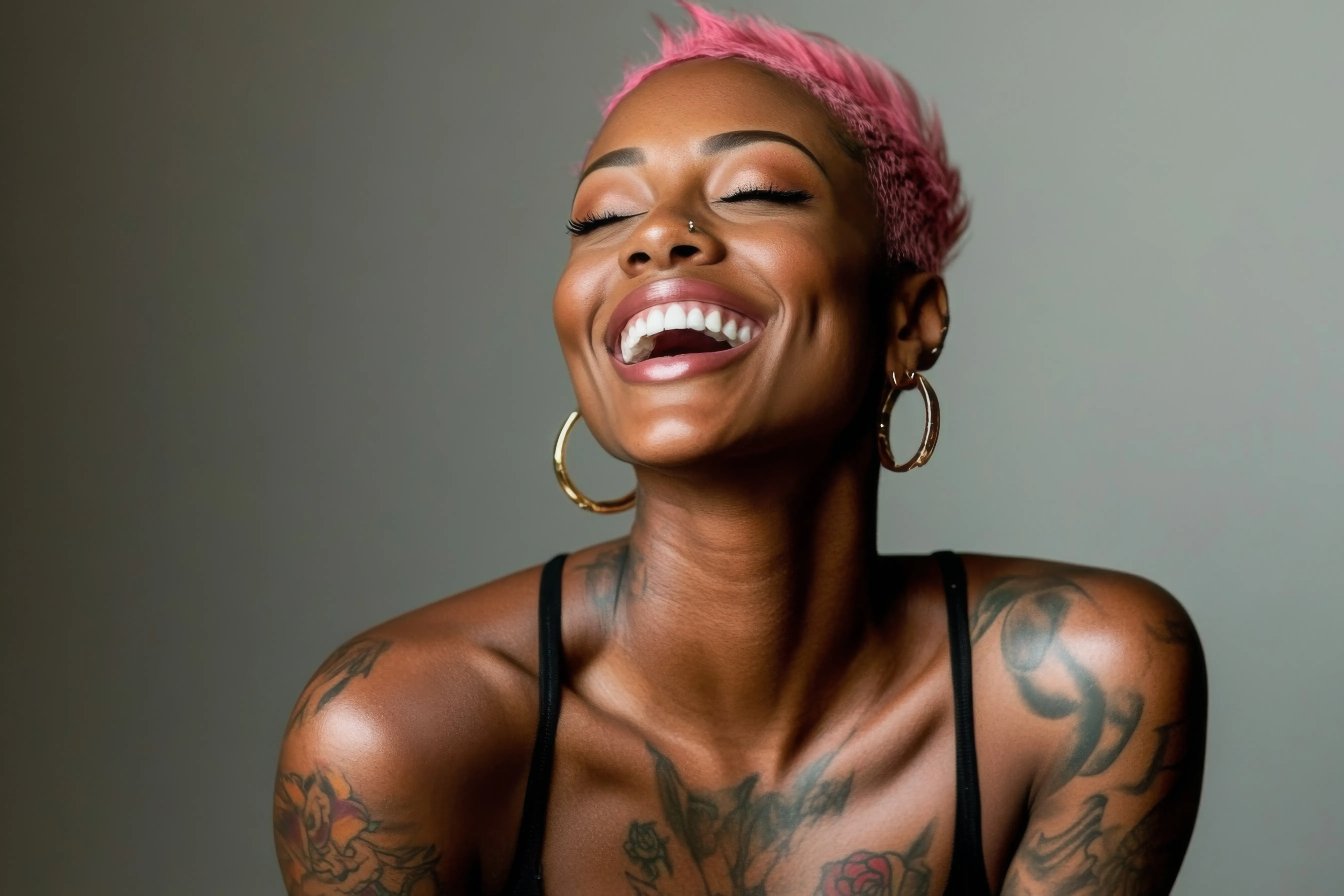 A joyful Black woman with short pink hair and hoop earrings